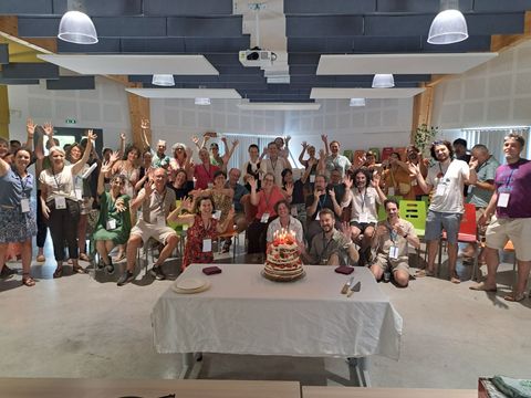 Une rencontre collective des entrepreneur·es de Solstice, bras levés autour d'un gâteau